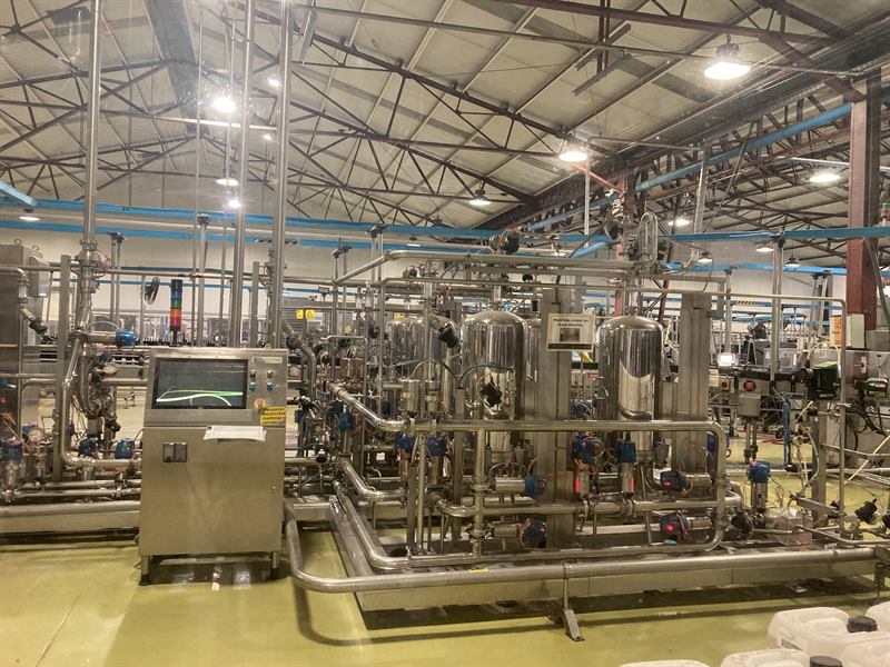 Planta de producción con estanques de acero inoxidable, tuberías y un terminal de control