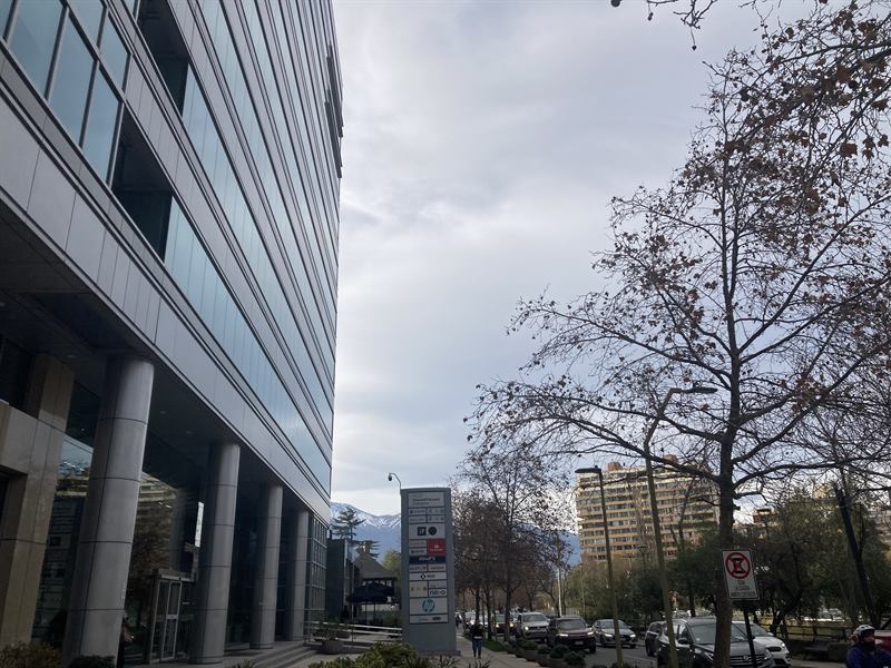 Torre de oficinas en Santiago y calle arbolada, con la cordillera de los Andes al fondo
