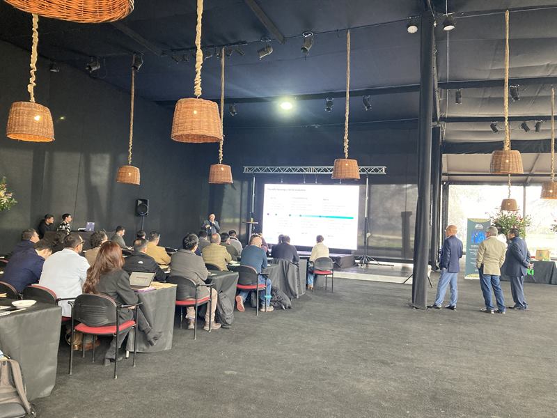 Un presentador en el escenario con asistentes de pie al fondo de la sala