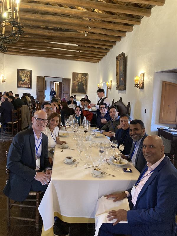 Delegados reunidos en torno a una mesa larga para el almuerzo en un comedor colonial